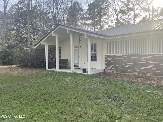 view of side of property featuring a yard, board and batten siding, and a patio area