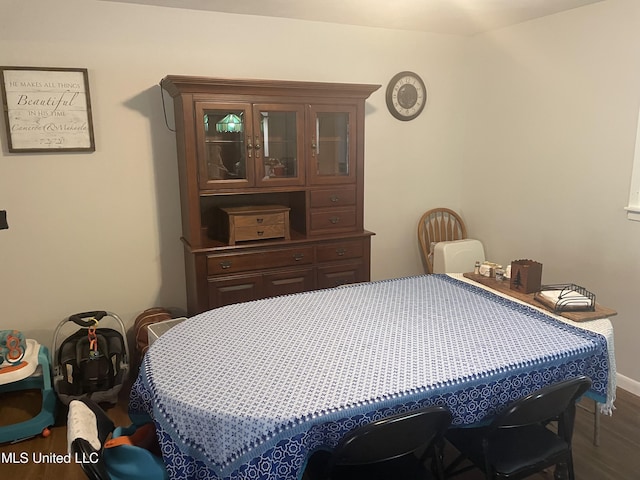 bedroom with baseboards and dark wood-type flooring