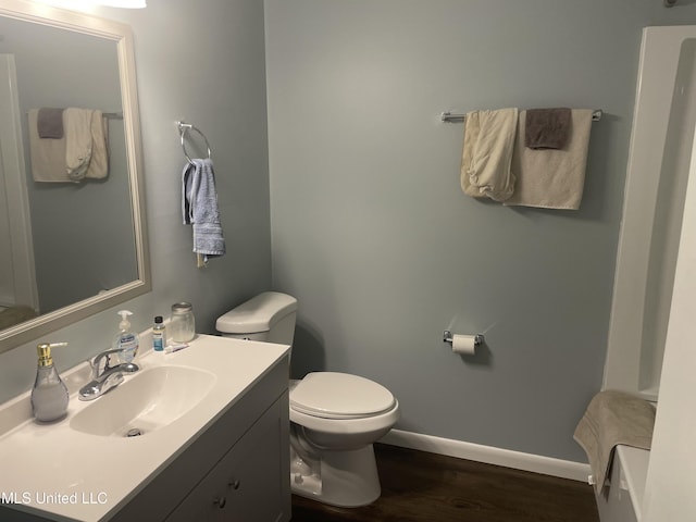 bathroom with vanity, toilet, wood finished floors, and baseboards