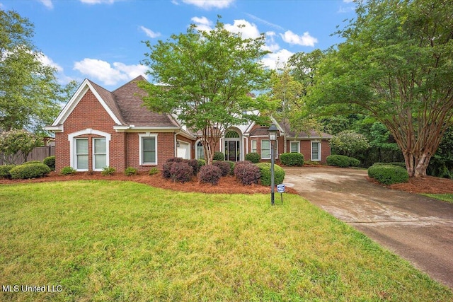 view of front facade featuring driveway, brick siding, fence, a front lawn, and an attached garage