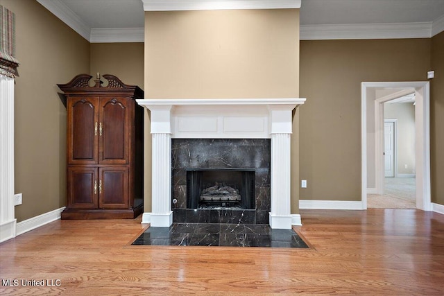 interior details featuring a tiled fireplace, ornamental molding, and wood-type flooring