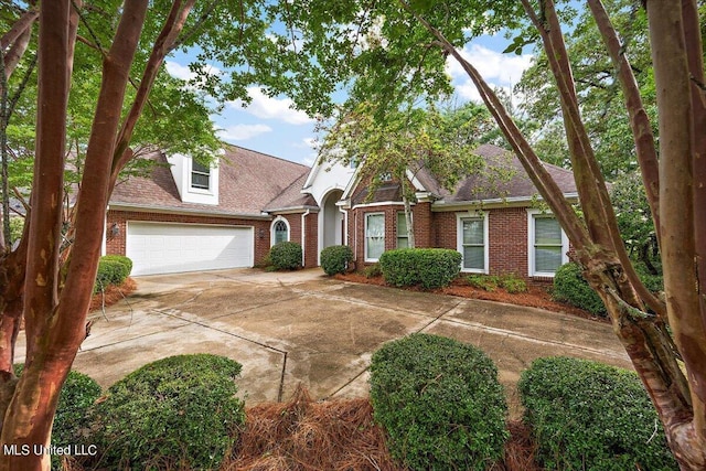 view of front of home with roof with shingles, an attached garage, concrete driveway, and brick siding