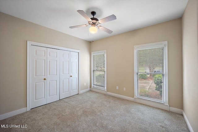 unfurnished bedroom with light carpet, a closet, and ceiling fan