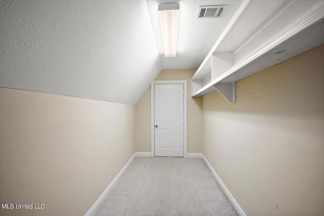 spacious closet featuring lofted ceiling and light colored carpet