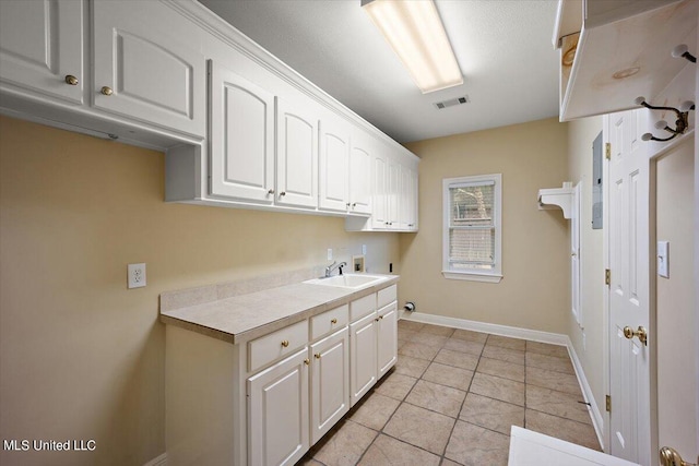 laundry area with cabinets, hookup for a washing machine, sink, and light tile patterned flooring