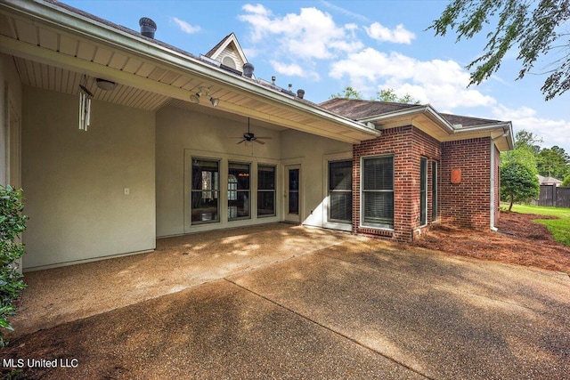 rear view of house with brick siding, a ceiling fan, a patio area, and stucco siding