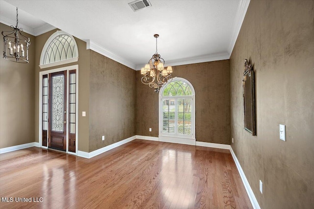 foyer with crown molding, a notable chandelier, and wood-type flooring