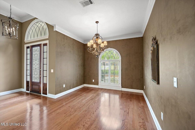 foyer featuring an inviting chandelier, baseboards, wood finished floors, and visible vents