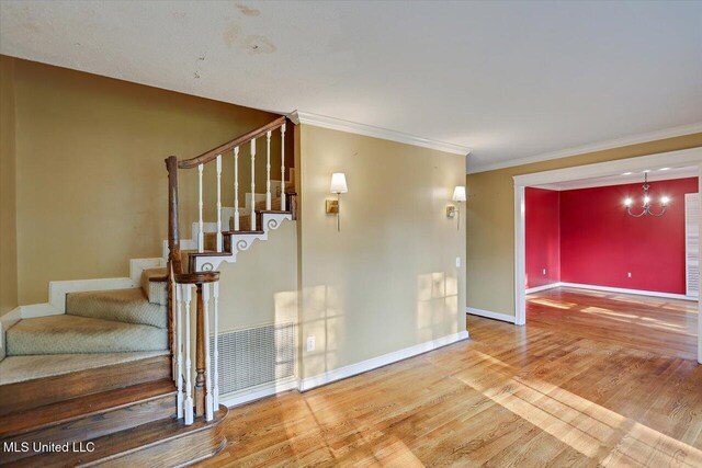 223 Hannah Dr, Clinton, MS 39056 - stairs featuring wood finished floors, baseboards, a chandelier, and ornamental molding