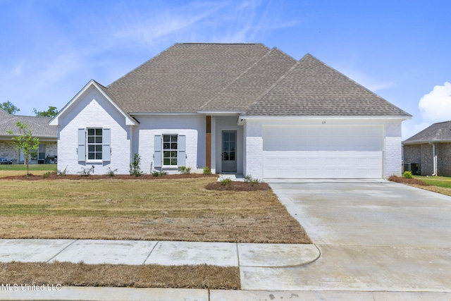 view of front of home with central air condition unit, a front lawn, and a garage