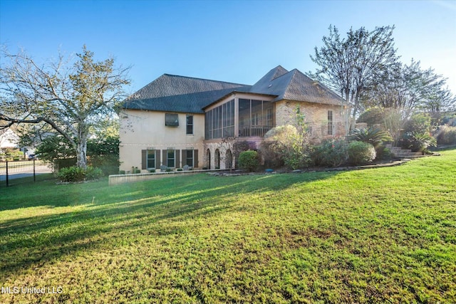 rear view of property with a sunroom and a lawn