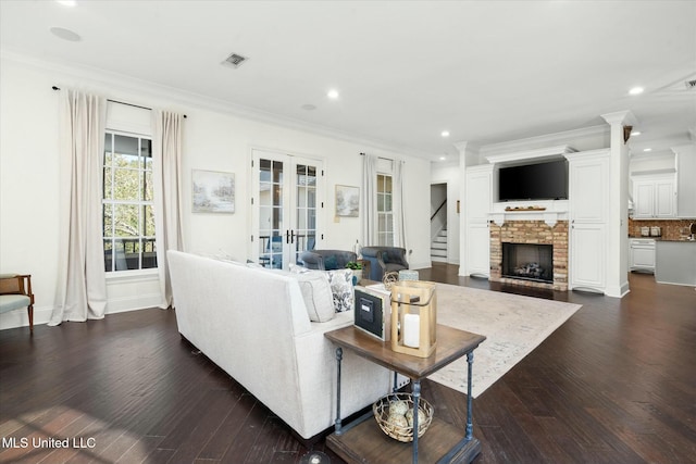 living room featuring a fireplace, crown molding, dark wood-type flooring, and french doors