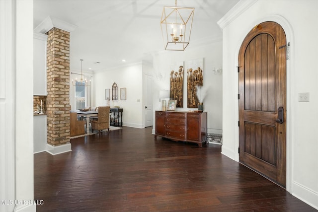 foyer with crown molding, dark wood-type flooring, and a notable chandelier