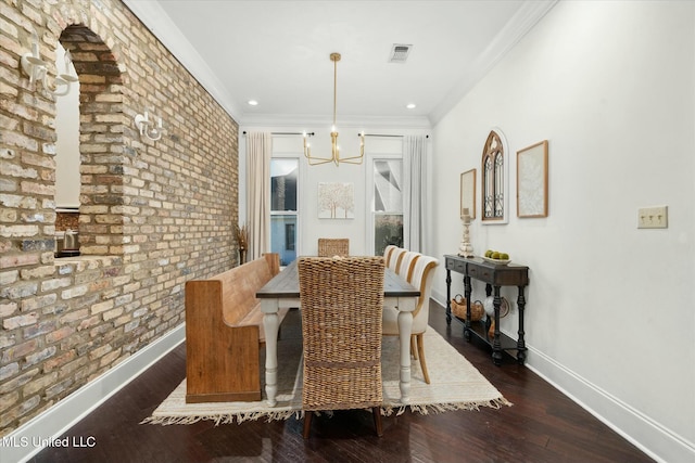 dining room featuring a notable chandelier, dark hardwood / wood-style flooring, ornamental molding, and brick wall