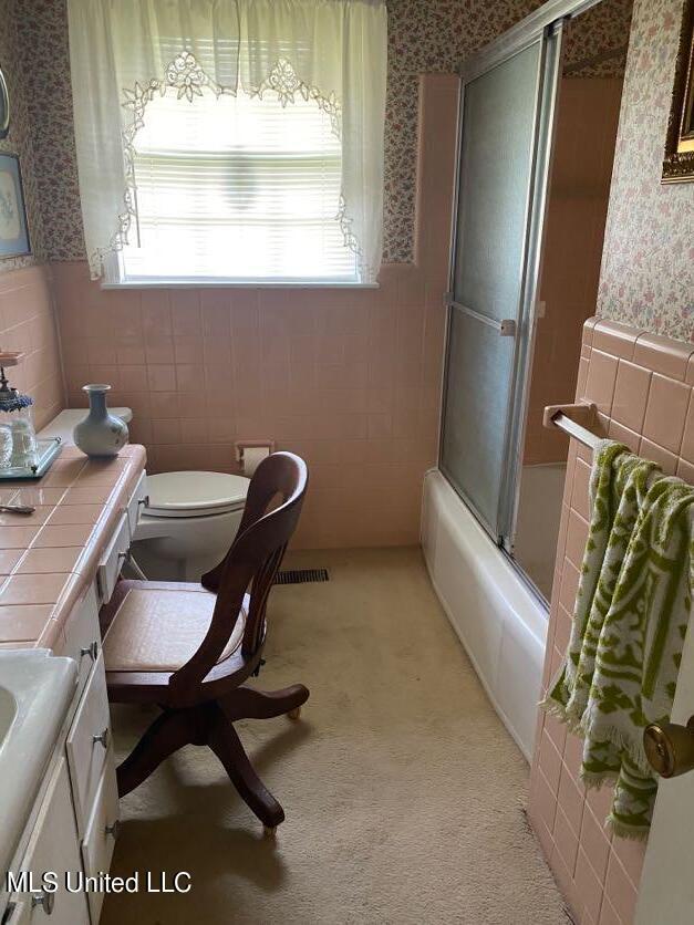 22 N Joliffe St, Eupora, MS 39744 - bathroom with wainscoting, vanity, toilet, wallpapered walls, and tile walls