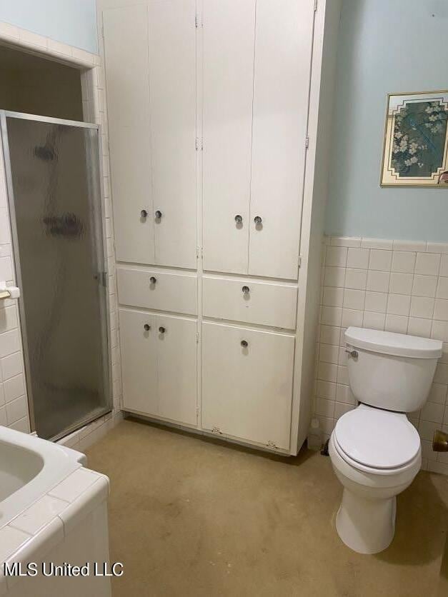22 N Joliffe St, Eupora, MS 39744 - full bath with a wainscoted wall, a stall shower, toilet, and tile walls