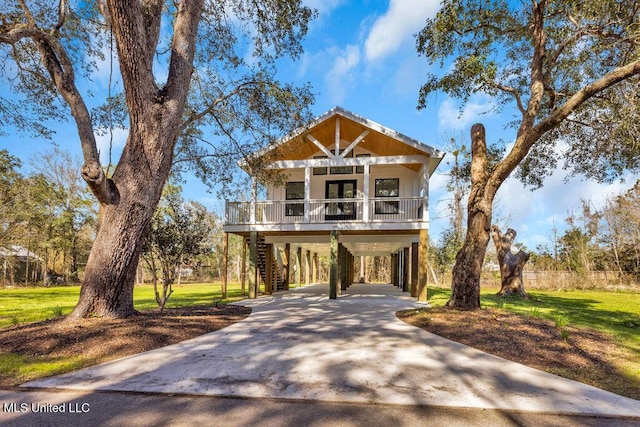 beach home featuring covered porch, a carport, a front lawn, and concrete driveway