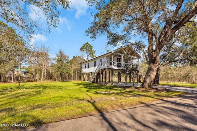 view of side of property with stairs and a yard