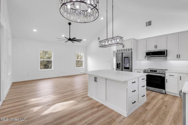 kitchen with appliances with stainless steel finishes, a center island, hanging light fixtures, light countertops, and white cabinetry