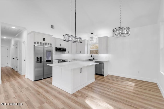 kitchen featuring a kitchen island, white cabinetry, light countertops, appliances with stainless steel finishes, and decorative light fixtures