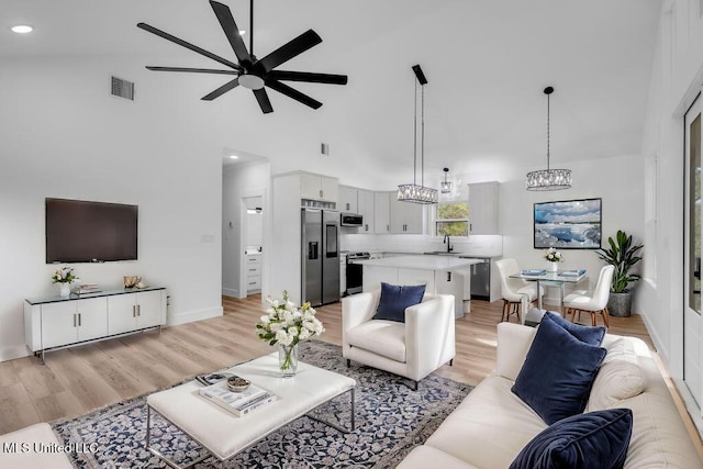 living area featuring visible vents, baseboards, light wood-style flooring, ceiling fan, and high vaulted ceiling