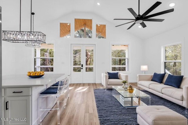 living area with light wood-style floors, plenty of natural light, high vaulted ceiling, and french doors