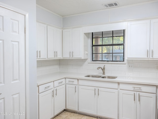 kitchen featuring sink, white cabinets, crown molding, decorative backsplash, and light tile patterned floors