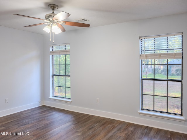 spare room featuring a healthy amount of sunlight, dark wood-type flooring, and ceiling fan