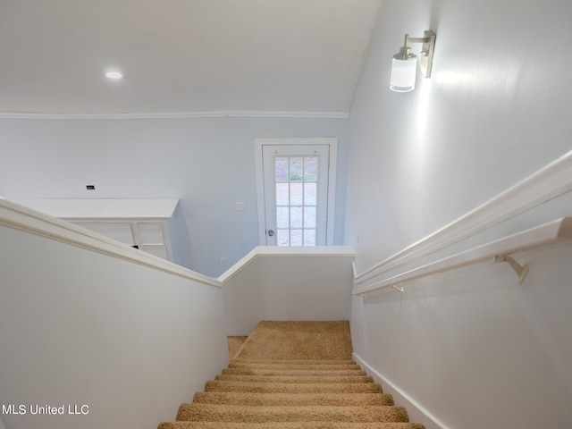 staircase with ornamental molding and lofted ceiling