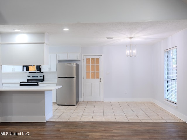 kitchen with light hardwood / wood-style floors, appliances with stainless steel finishes, pendant lighting, and white cabinets