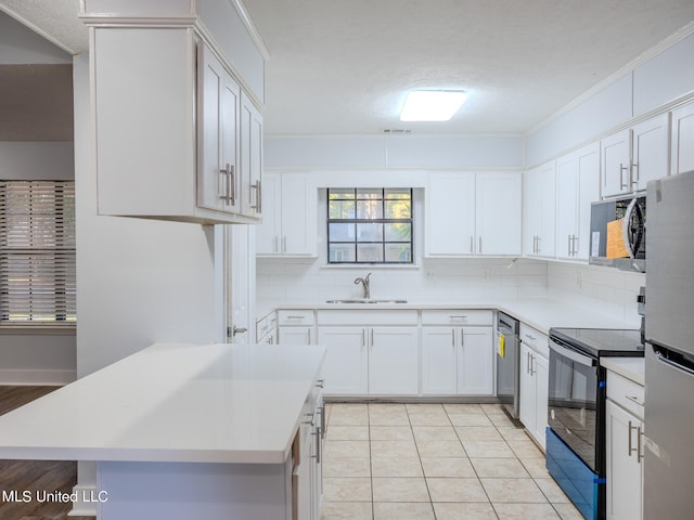 kitchen with appliances with stainless steel finishes, sink, white cabinetry, decorative backsplash, and light tile patterned floors