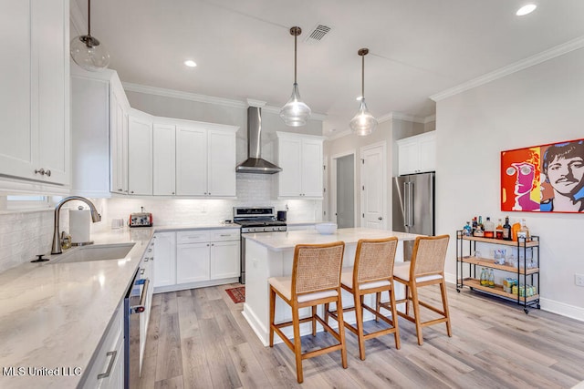 kitchen with wall chimney range hood, white cabinets, stainless steel appliances, and sink