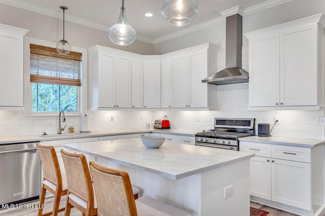 kitchen with wall chimney exhaust hood, appliances with stainless steel finishes, a center island, and white cabinets