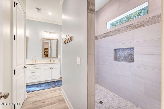 bathroom featuring vanity, hardwood / wood-style floors, ornamental molding, and tiled shower