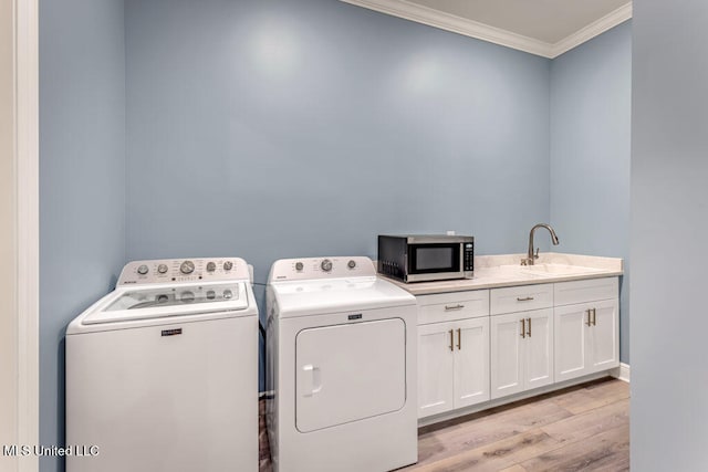 laundry room featuring cabinets, light wood-type flooring, independent washer and dryer, ornamental molding, and sink