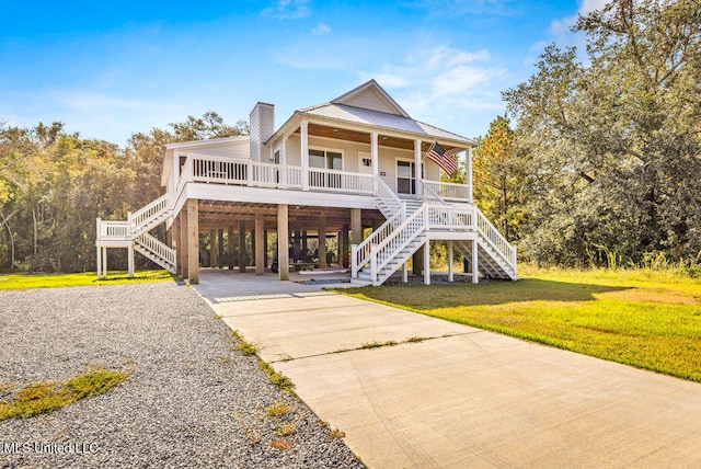 raised beach house featuring a carport, a front lawn, and a porch