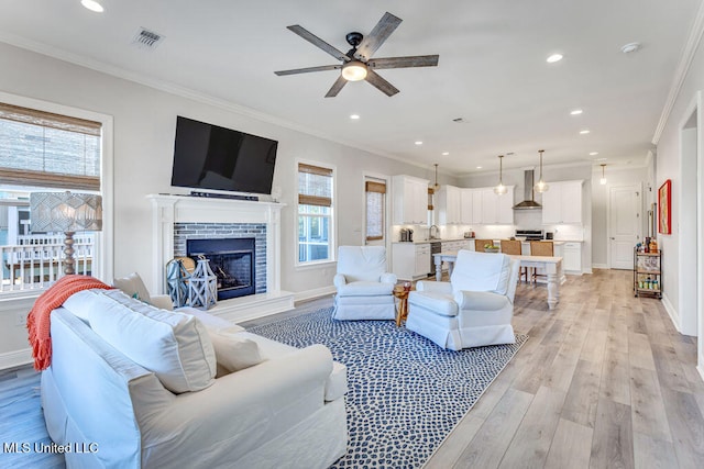 living room with crown molding, a brick fireplace, light hardwood / wood-style floors, and plenty of natural light