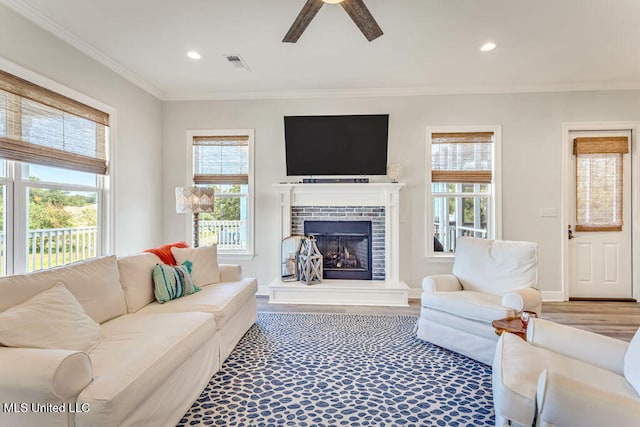 living room featuring crown molding, a fireplace, wood-type flooring, and plenty of natural light