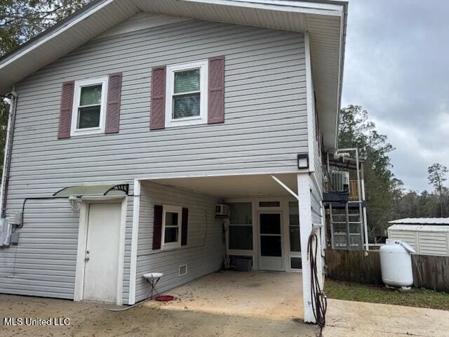 rear view of property featuring a carport and an AC wall unit