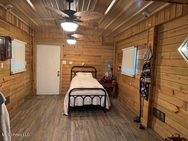 bedroom featuring wooden walls, dark wood-type flooring, and wood ceiling