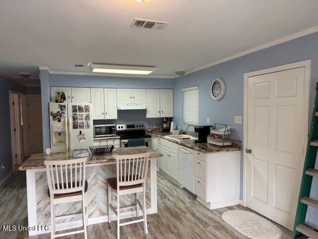 kitchen with sink, stainless steel appliances, light wood-type flooring, white cabinets, and ornamental molding