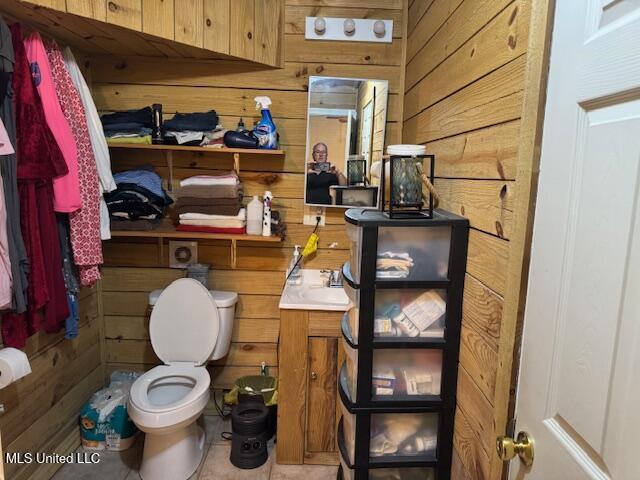 bathroom featuring tile patterned floors, vanity, toilet, and wooden walls