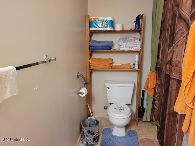 bathroom featuring baseboards and toilet
