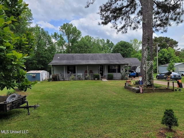 view of front of property featuring covered porch, an outdoor structure, a front lawn, and a shed