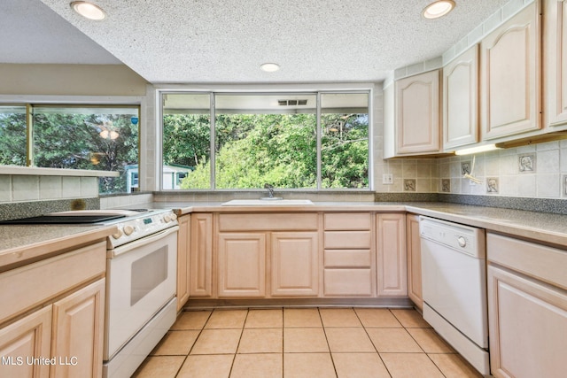 kitchen with light tile patterned flooring, light brown cabinetry, plenty of natural light, and white appliances