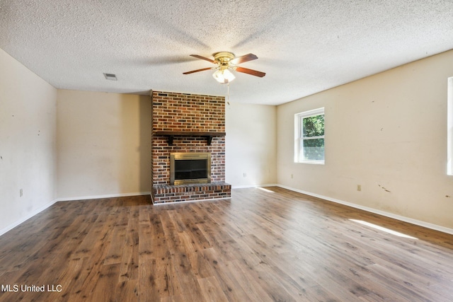 unfurnished living room with a textured ceiling, a brick fireplace, and dark hardwood / wood-style floors