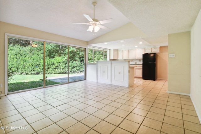 kitchen with white cabinets, a textured ceiling, light tile patterned floors, and black fridge