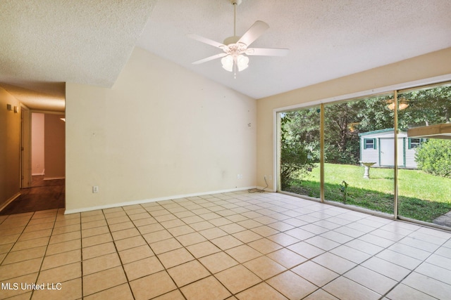 spare room featuring ceiling fan, lofted ceiling, a textured ceiling, and light tile patterned flooring