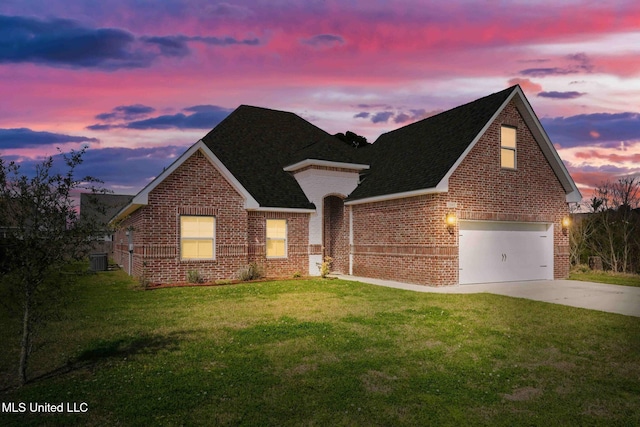 view of front of property with brick siding, a garage, concrete driveway, and a yard