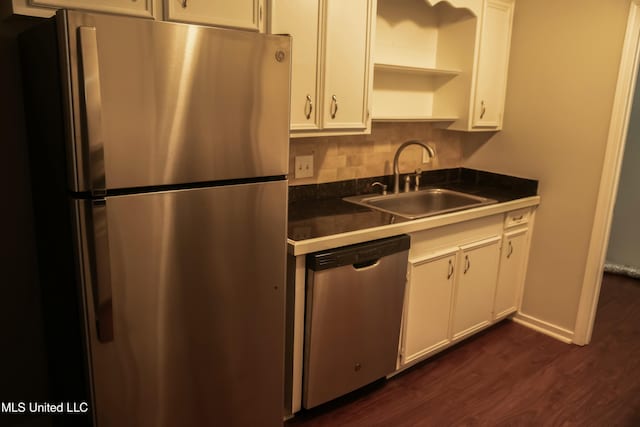 kitchen featuring dark wood-type flooring, sink, tasteful backsplash, stainless steel appliances, and white cabinets